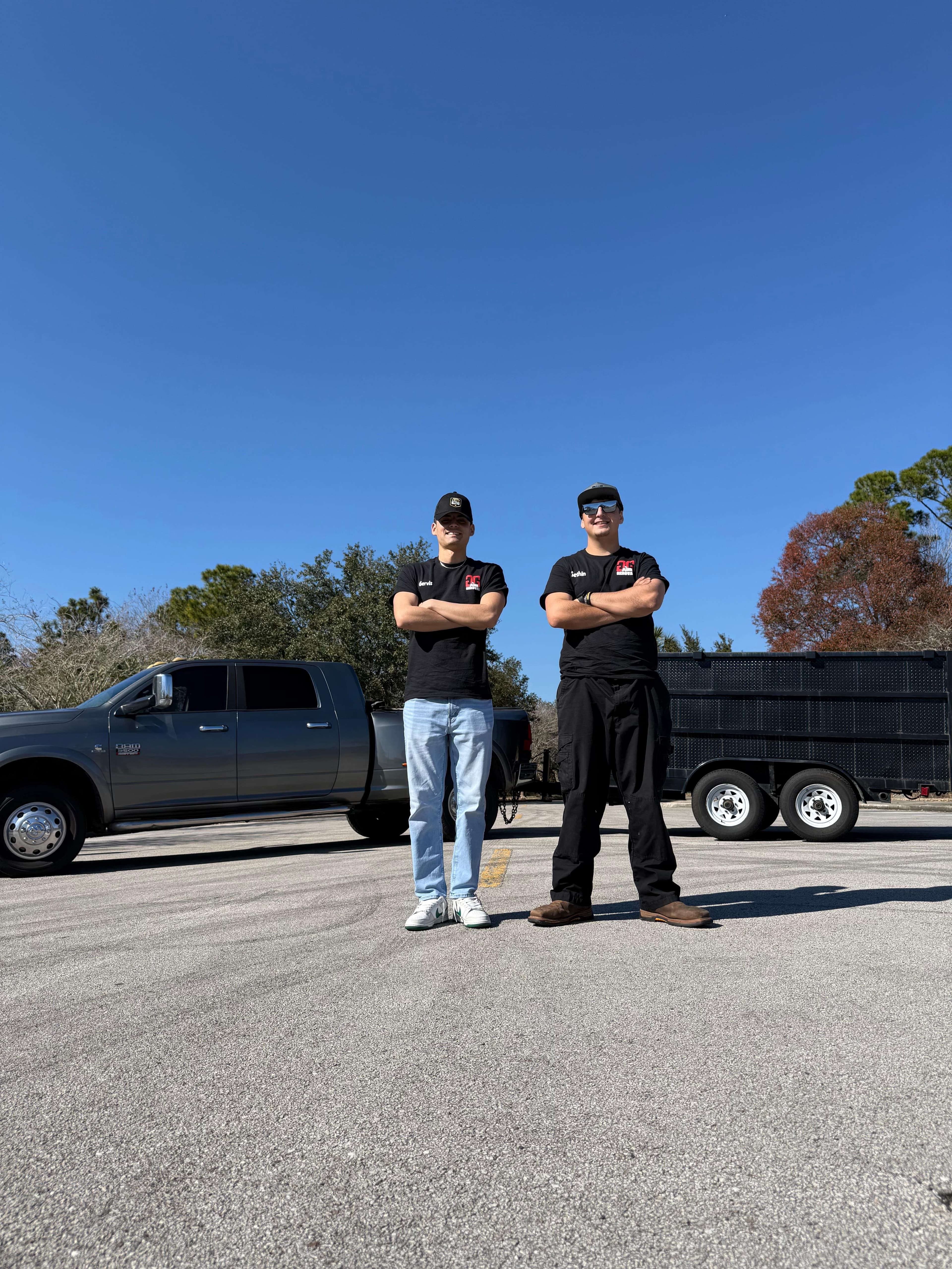 G&G Junk Removal team standing in front of their truck and trailer